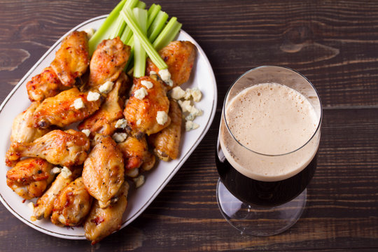 Glass of dark beer and siracha buffalo chicken wings. Ale and food