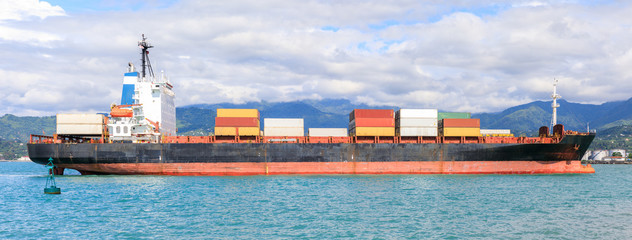 A small container in the port of Batumi on a background of mountains