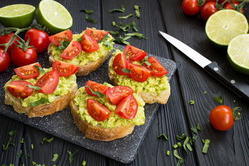 Vegetarian sandwiches  with tomatoes  and avocado  on  the black  wooden background