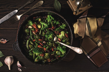Vegetable stew in a frying pan on a dark wooden table
