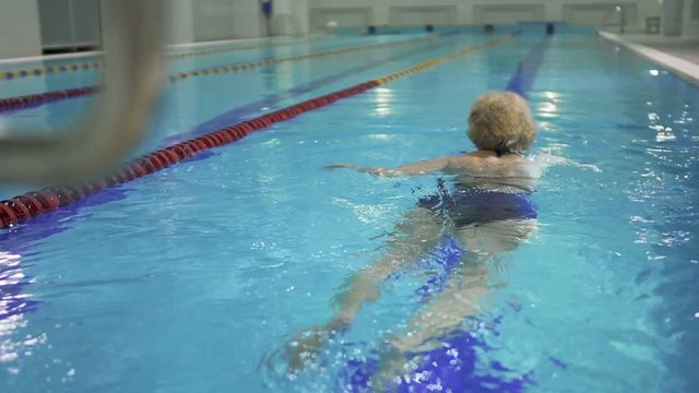 Elderly woman swims in the pool