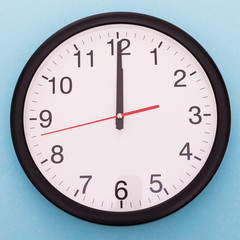 Wall clock isolated on blue background. Twelve o'clock