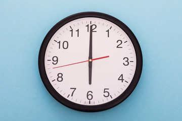 Big wall clock isolated on blue background. Six o'clock.