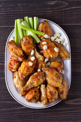 Buffalo chicken wings on white plate on wooden background