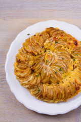 Potato gratin on white plate. Baked potato slices with creamy sauce. View from above, top, vertical