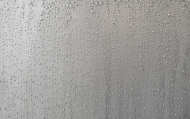Many silver liquid drops scattered on a silver background.