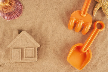 Molded sand house and plastic toys, laying on the beach. © michelaubryphoto