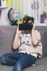 Naklejka premium Boy plays with virtual reality glasses, indoors. Digital virtual reality device