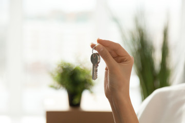 Female hand holding house key, customer buying real estate, woman buyer becoming new first time home owner, rental property purchase, mortgage investment loan, ownership concept, close up view