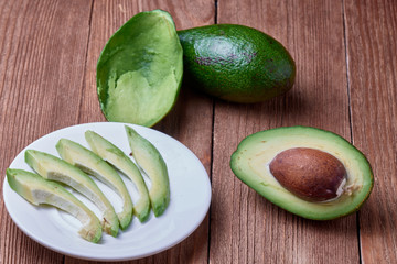 Delicious ripe avocado on a wooden background. Pieces of avocado on a plate. Organic food.