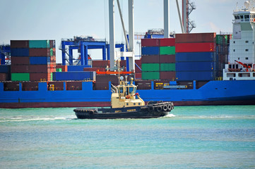 Tugboat assisting container cargo ship