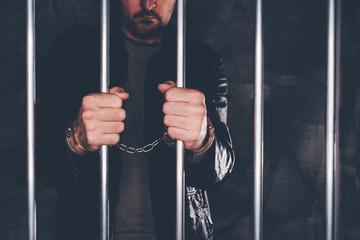 Handcuffed man behind prison bars