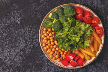 Bowl with vegetables and chickpea on a dark  background.