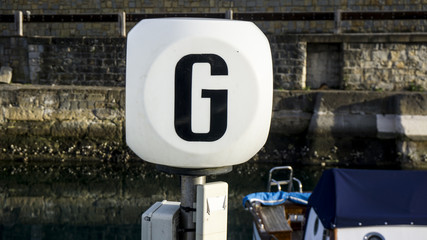 Letter G on a white box in an italien harbor