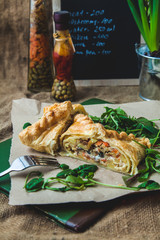 puff pastry stuffed with meat, carrots, potato pie, decorated with rucola, on a dark background Background for postcard. Menu, restaurant, recipe concept, served in. Rustik stile