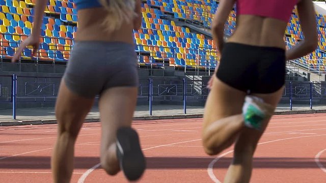 Multiethnic female athletes running on stadium on sunny day, workout and health