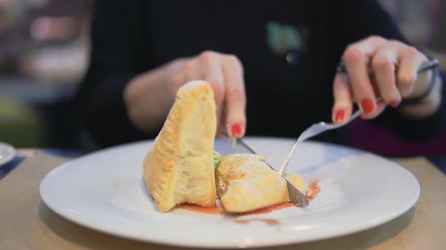 A middle-aged woman eats dessert in a cafe.