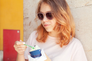 Teenage girl in sunglasses eats ice cream