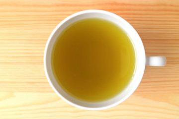 Top View of a Cup of Hot Japanese Green Tea Served on Natural Color Wooden Table 