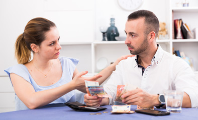 Fototapeta premium Young female and her husband are counting finance at the table