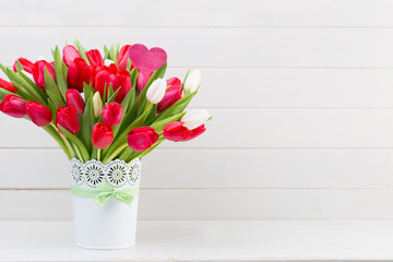 Fresh red tulip flowers bouquet on shelf in front of wooden wall.
