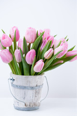 Spring easter tulips in bucket on white vintage background.