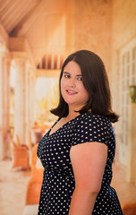 Close up of young beautiful plus size model in black dress, xxl woman in blurred studio background