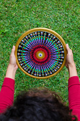 Woman's hands holding a mandala, green grass background, high angle view