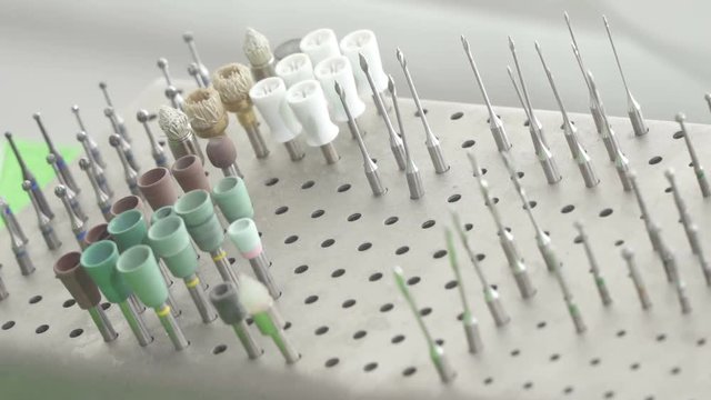 Close-Up Of Dentist's hand in gloves selecting a bur from set in a shelf