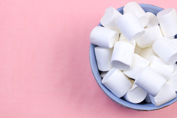 Marshmallows in blue plate on pastel pink background.