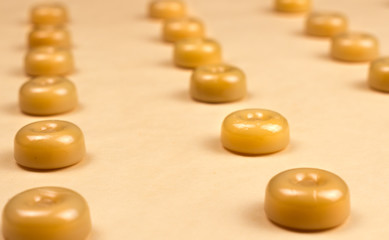 Sweet caramel candys on pastel yellow surface.