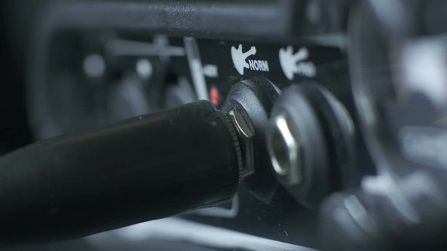Close-up hand plugging xlr microphone or guitar cable in amplifier connector of audio interface. Side view. Professional equipment for sound recording in studio