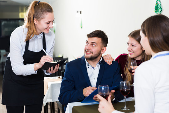 Woman waiter is taking order from clients