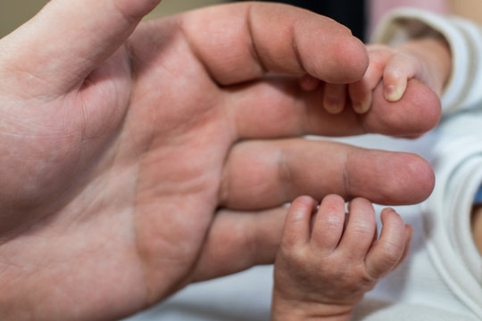 Hand eines Babys greift nach Papas Fingern