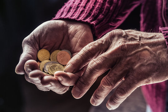 Pensioner man holding in hands euro coins. Theme of low pensions.