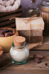 Natural cosmetic oil, sea salt and natural handmade soap with cocoa beans on rustic wooden background