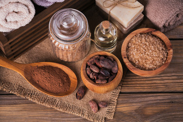 Natural cosmetic oil, sea salt and natural handmade soap with cocoa beans on rustic wooden background