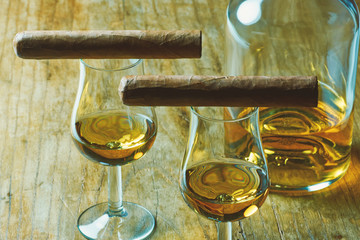 Close-up photo two cigar, a bottle of alcohol and a two glass of whiskey