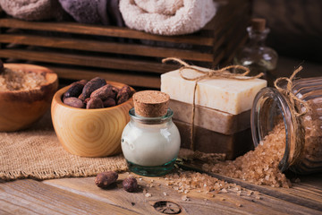 Natural cosmetic oil, sea salt and natural handmade soap with cocoa beans on rustic wooden background