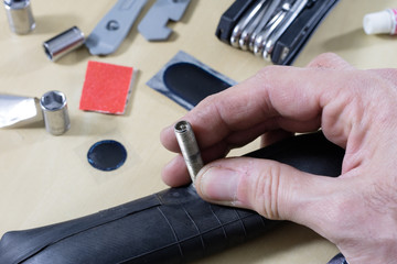 Obraz premium Bicycle breakdown during the trip. Sticking a bicycle tube in a workshop. Mechanic fixing a bicycle tube.