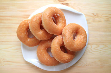 Top View of Sugar-glazed Doughnuts Served on White Plate on Wooden Table 