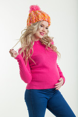 Blonde happy pregnant woman is wearing warm winter clothes hat and sweater isolated on white background