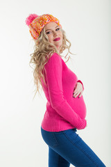 Blonde happy pregnant woman is wearing warm winter clothes hat and sweater isolated on white background