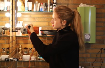 Young woman in bathroom with drilling machine.