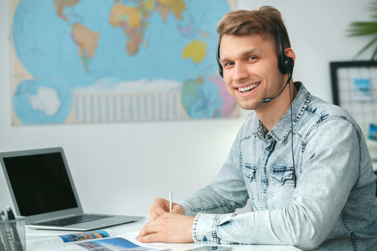 Young male travel agent consultant in tour agency wearing headset