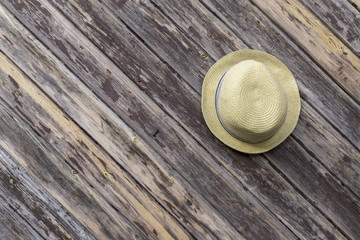 straw hat on brown wood wall. Vintage style Use it as a background or holiday concept.