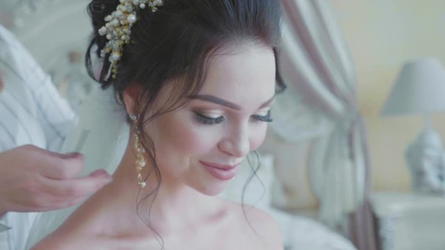 Stylist inserting a veil into the brides hair before the wedding