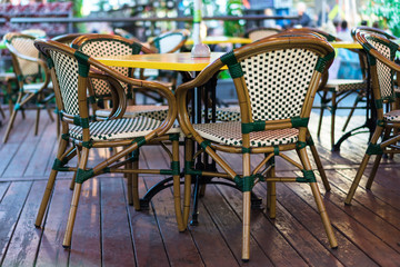 outdoor cafe, yellow tables, wicker chairs, wooden floor