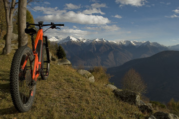 ebike, e-bike, electric bicycle, high mountain, leaning against tree, detail of handlebars, wheels, saddle, display, alps landscape, snow covered tops, autumn, winter, Antrona Valley, Piedmont, Italy