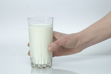 A glass of milk in a hand on a white background.